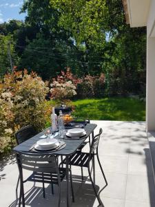 einen schwarzen Tisch mit vier Stühlen auf einer Terrasse in der Unterkunft Maisons T2 avec jardins privatifs - 10mn de la plage et 5mn du village - Casa di i trinelli in Vescovato