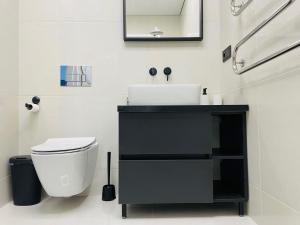 a bathroom with a black sink and a toilet at Alto Turtas Apartamentai in Šiauliai