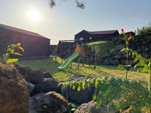 a playground with a green slide in a yard at Kuanza Nature Experience, Fajã do Belo in Fajã da Caldeira de Santo Cristo
