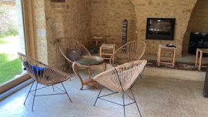 Zimmer mit 4 Stühlen, einem TV und einem Tisch in der Unterkunft Pépite en Périgord 10-12 couchages, piscine chauffée, rénovée par architecte in Bouzic