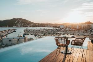 a rooftop pool with chairs and a view of a harbor at Aguas de Ibiza Grand Luxe Hotel - Small Luxury Hotel of the World in Santa Eularia des Riu