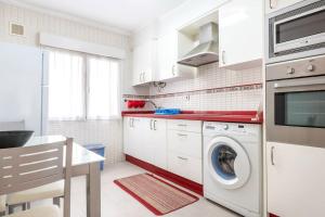 una cocina blanca con lavadora. en MyHouseSpain - Precioso piso cerca de la playa, en Gijón