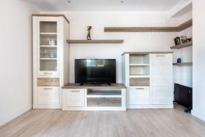 a living room with a tv and white cabinets at MyHouseSpain - Precioso piso cerca de la playa in Gijón