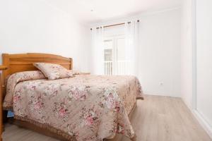 1 dormitorio con 1 cama con colcha de flores y ventana en MyHouseSpain - Precioso piso cerca de la playa, en Gijón