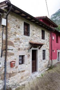 uma casa de pedra com uma porta vermelha e janelas em La Seronda de Villaorille - Las Casas del Oso 