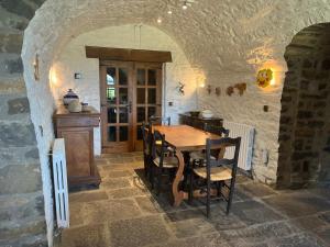 uma cozinha com uma mesa de madeira num quarto de pedra em La Abadia em Coscojuela de Sobrarbe