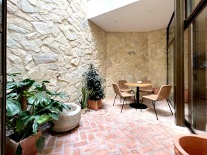 Pokój z kamienną ścianą, stołem i krzesłami w obiekcie Arcos de Medina - Apartamentos premium w Kordobie