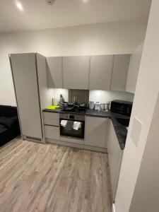 una pequeña cocina con armarios blancos y suelo de madera. en 1 bed apartment in the heart of Staines town centre, en Staines upon Thames