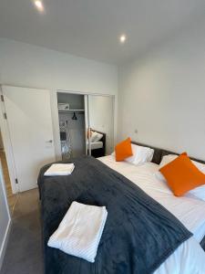 2 camas en una habitación con almohadas naranjas. en 1 bed apartment in the heart of Staines town centre, en Staines upon Thames