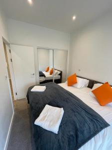 twee bedden in een kamer met oranje kussens erop bij 1 bed apartment in the heart of Staines town centre in Staines upon Thames
