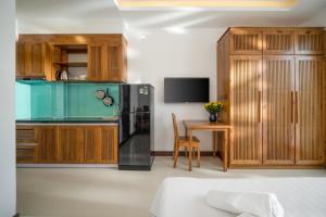 uma cozinha com armários de madeira, um frigorífico e uma mesa em Carol Homestay & Apartment Đà Nẵng 4 em Da Nang