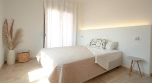 een witte slaapkamer met een bed en een raam bij Onos - 2 bedroom 2 bathroom penthouse with terrace in Old Town in Kalamata