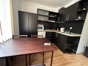 una cocina con mesa de madera y una cocina con armarios negros en Siana 4 Apartment (15), en Sveti Vlas
