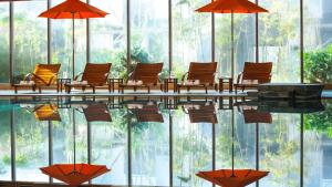 une piscine avec des chaises et des parasols dans un bâtiment dans l'établissement Renaissance Wuhan Hotel, à Wuhan