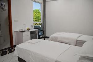 a bedroom with two beds and a desk and a window at EQUATOR RETREAT in Fuvahmulah