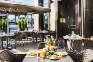 um restaurante ao ar livre com mesas e cadeiras com comida em Welcome Parkhotel Euskirchen em Euskirchen