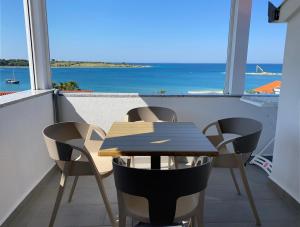 una mesa y sillas en un balcón con vistas al océano en Emanuela 1, en Novalja
