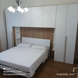 a bedroom with a white bed and white cabinets at DESTINAZIONE PARADISO in Piombino