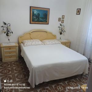 a bedroom with a white bed and two night stands at DESTINAZIONE PARADISO in Piombino
