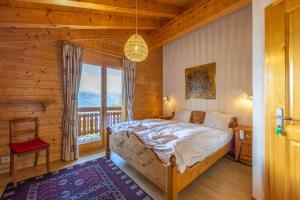 a bedroom with a bed and a large window at Chalet Le Papillon - Calm, sunny, spacious in Nendaz
