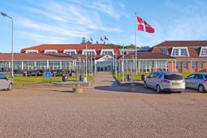 a building with cars parked in a parking lot with a canadian flag at Hotel Pinenhus in Glyngøre