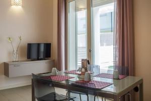 a living room with a glass table and a television at Residence Millecento in Cesenatico