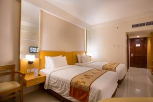 a hotel room with two beds and a chair at Golden Palace Hotel Lombok in Mataram