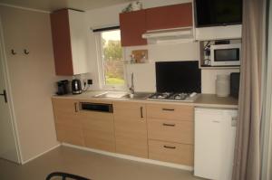 uma pequena cozinha com armários de madeira e uma janela em Veld lodge em Schoonloo