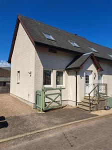 ein weißes Gebäude mit einem Tor und einem Zaun in der Unterkunft Sugarloaf in Fort William