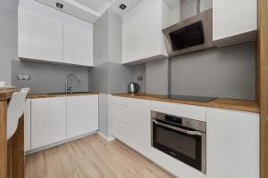 a kitchen with white cabinets and a sink at Modern Studio with Balcony for 4 Guests in Wrocław by Renters in Wrocław