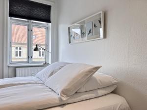 a white bedroom with a bed with pillows and a window at Two Bedroom Apartment In Copenhagen, Woltersgade 9, in Copenhagen