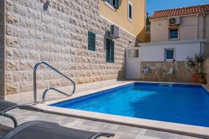 una piscina frente a un edificio con una pared de ladrillo en Luxury apartment "Blue Diamond", en Postira