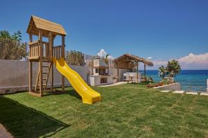 un parco giochi con scivolo in un cortile vicino all'oceano di Ducato di Zante Luxury Beach Villa a Kypseli