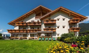 a large white building with balconies and a yard at Hotel Waldheim in Valle Di Casies