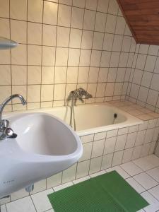 eine Badewanne mit einem Wasserhahn und einem Waschbecken in der Unterkunft Bonita Apartman in Balatonberény