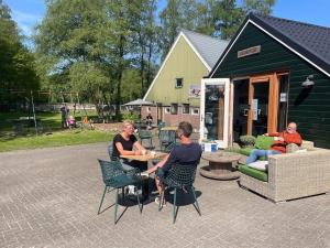 Veld lodge في Schoonloo: مجموعة من الناس يجلسون على طاولة أمام المنزل