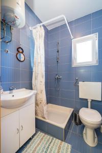 a blue tiled bathroom with a toilet and a sink at House Harry near Supermarket and Center in Novalja