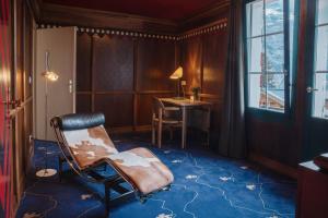 a room with a chair and a desk and a window at Hotel Drei Berge in Mürren