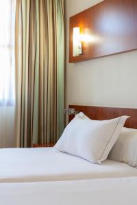 1 dormitorio con 1 cama con sábanas blancas y espejo en Senator Huelva en Huelva