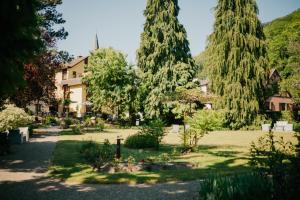 a garden with trees and a building in the background at L'AO Hôtel & Restaurant L'Aigle d'Or in Rimbach-près-Guebwiller