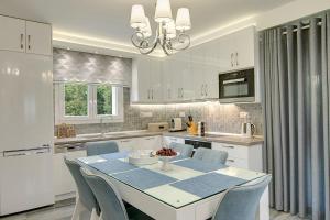 a white kitchen with a table and chairs in it at Azalea Villa Sani, Sani Luxury Villas Collection in Sani Beach
