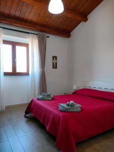 ein Schlafzimmer mit einem roten Bett mit Handtüchern darauf in der Unterkunft Perdanoa in Ghilarza