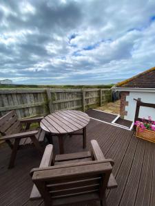 una terraza de madera con mesa de picnic y sillas en Fisherman's Daughter en Dorchester