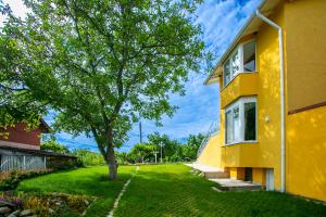 żółty dom z drzewem w ogrodzie w obiekcie Къща за гости Кала w mieście Patalenitsa