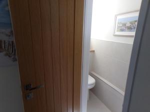 a door to a bathroom with a toilet and a window at 3TheDome - Luxury Ground Floor Apartment opposite the Beach, Barton on Sea in Barton on Sea