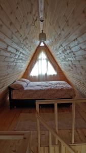 Bett in einem Holzzimmer mit Fenster in der Unterkunft Çatalkaya Bungolov in Kireçhane