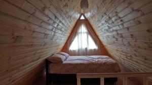 Cama pequeña en habitación de madera con ventana en Çatalkaya Bungolov, en Kireçhane