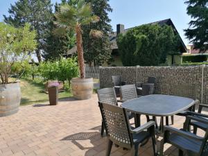 eine Terrasse mit einem Tisch, Stühlen und einer Palme in der Unterkunft Ferienwohnung Weingut Brutscher in Roschbach