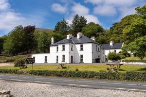 una casa bianca sul ciglio di una strada di The guest wing at kylemore house a Kylemore