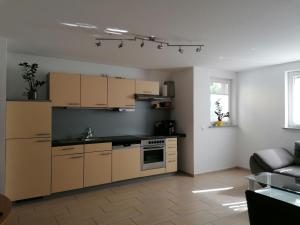 a kitchen with brown cabinets and a couch in a room at Ferienwohnung Weingut Brutscher in Roschbach